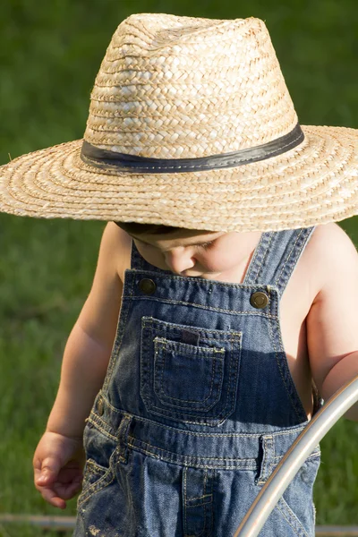 Ein Junge mit Strohhut, ein junger Gärtner, der den Frühling genießt — Stockfoto