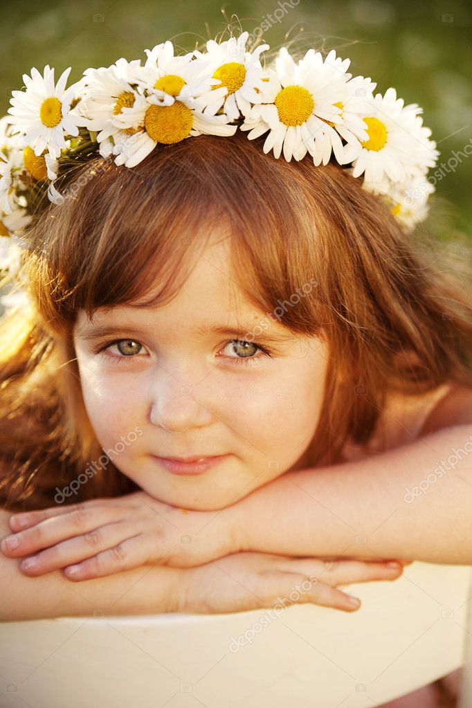 Indah bayi perempuan kecil dengan bunga aster di kepalanya 