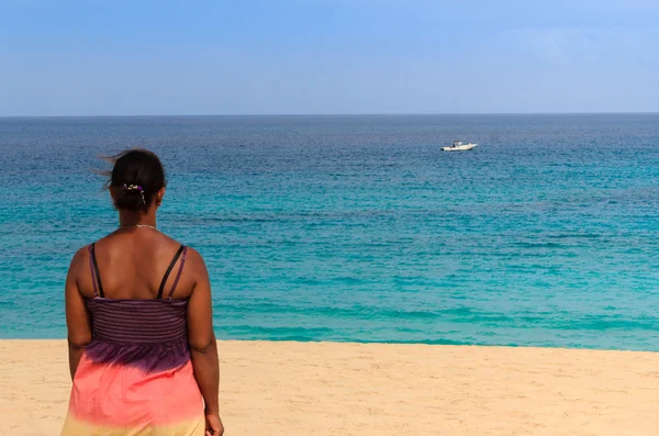 Расслабляющая пляжная женщина смотрит на лодку — стоковое фото