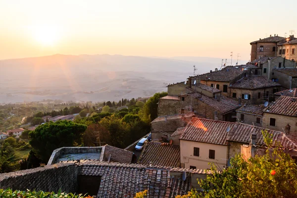 Puesta de sol y rayos de luz en la pequeña ciudad de Volterra al atardecer en Tus — Foto de Stock