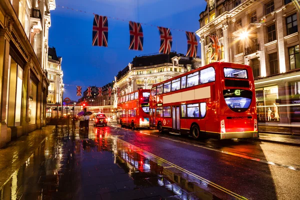 Κόκκινο λεωφορείο στο δρόμο του Λονδίνου βροχών κατά τη νύχτα, ενωμένη τι Royalty Free Εικόνες Αρχείου