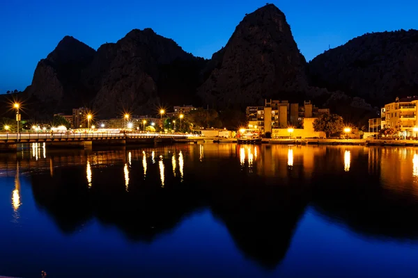 Siluetas de montaña y ciudad iluminada de Omis Reflexionando en —  Fotos de Stock