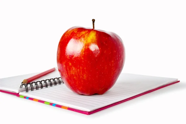 A red apple and pencil sitting on an opened notebook. — Stock Photo, Image