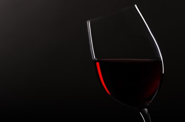 Wineglass with redwine before black background clipart