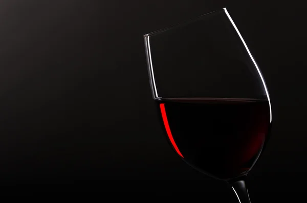 Weinglas mit Rotwein vor schwarzem Hintergrund — Stockfoto