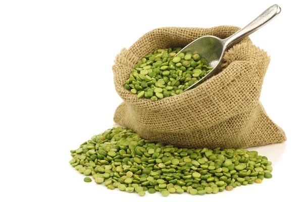 Split green peas in a burlap bag with an aluminum scoop — Stock Photo, Image