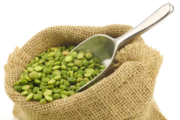 Split kacang polong hijau dalam tas goni dengan sendok aluminium — Stok Foto
