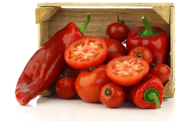 Rote Paprika, Tomaten und eine geschnittene Paprika in einer Holzkiste — Stockfoto