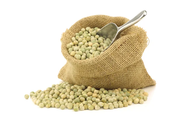 Green peas in a burlap bag with an aluminum scoop — Stock Photo, Image