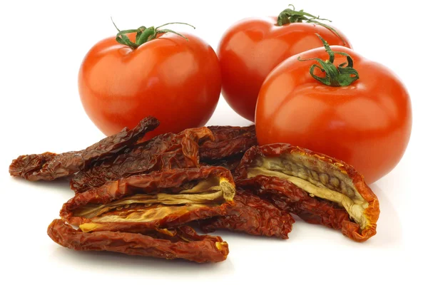 Some whole fresh tomatoes and sun dried tomato pieces — Stock Photo, Image