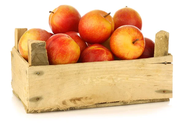 Red and yellow plums and a cut one in a wooden crate — Stock Photo, Image