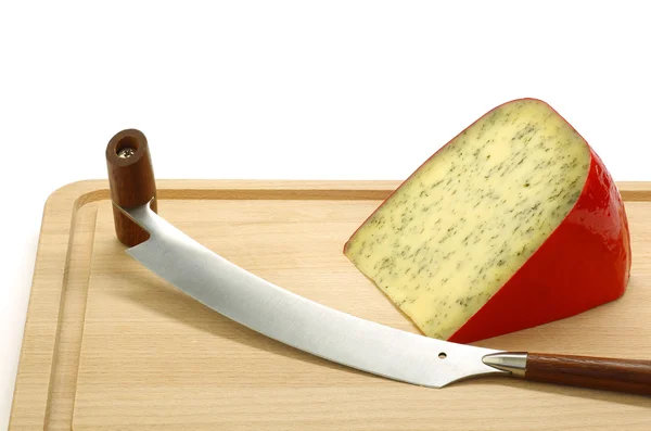 Piece of traditional frisian cheese with herbs and a cheese cutter — Stock Photo, Image