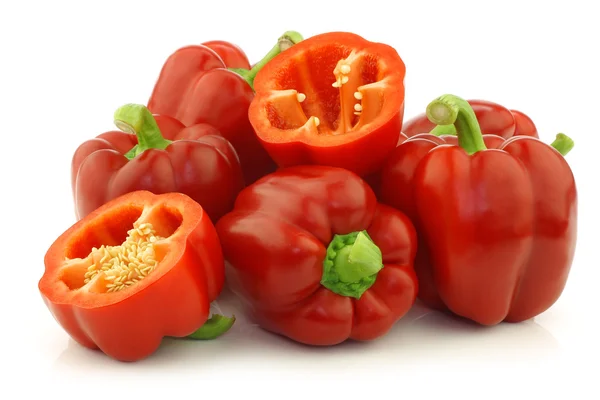 Fresh red bell peppers (capsicum) and a cut one — Stock Photo, Image