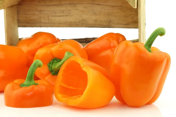 Fresh orange bell peppers and a cut one — Stock Photo, Image