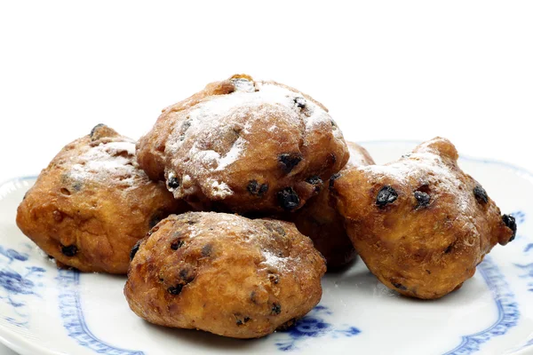 Powdered Dutch oliebollen baked with currents on a blue and white plate — Stock Photo, Image