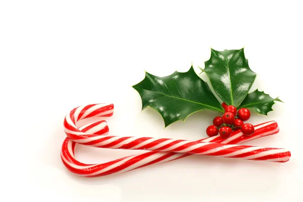 クリスマスのキャンディの杖はヒイラギの枝を持つ — ストック写真