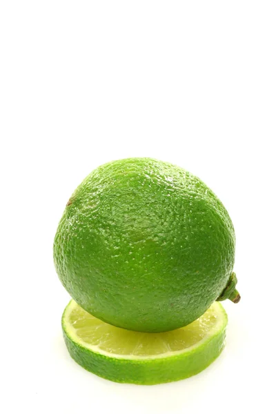 One whole lime fruit on top of a slice — Stock Photo, Image