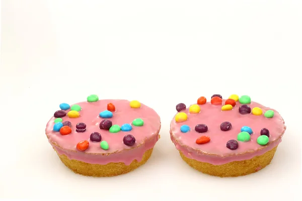 Cakes with pink icing and colorful sprinkles — Stock Photo, Image