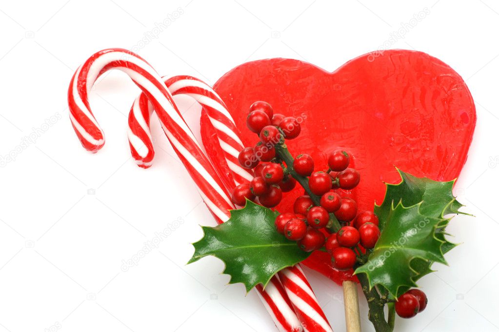 Christmas candy canes with a branch of holly on a red hart