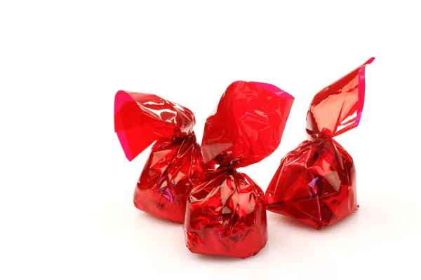Bonbons in rotes glänzendes Papier gewickelt — Stockfoto