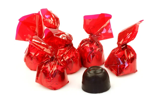 Bonbons wrapped in red shiny paper and one unwrapped ready to eat — Stock Photo, Image