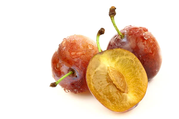 Deux prunes fraîches mûres et une coupée — Photo
