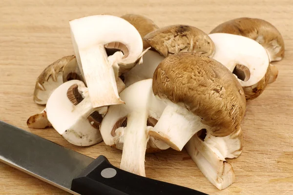 Un mucchio di champignons marroni tagliati e un coltello — Foto Stock