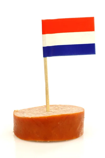 A piece of smoked sausage with a Dutch flag toothpick — Stock Photo, Image