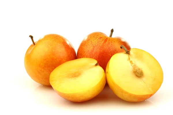 Two fresh plums and a cut one — Stock Photo, Image