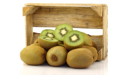 Green kiwi fruit and some cut ones in a wooden box clipart