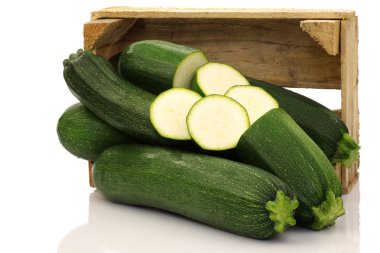 Fresh zucchini's and a cut one in a wooden box clipart