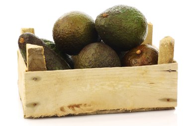 Fresh and ripe avocado's in a wooden crate clipart