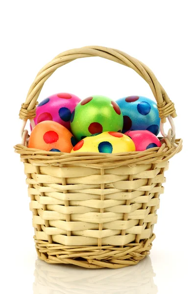 Wicker basket filled with colorful easter eggs — Stock Photo, Image