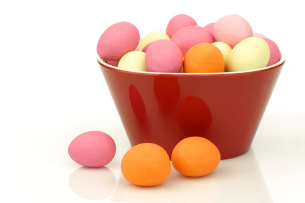 Barevné velikonoční vajíčko cukroví v červené misky — Stock fotografie