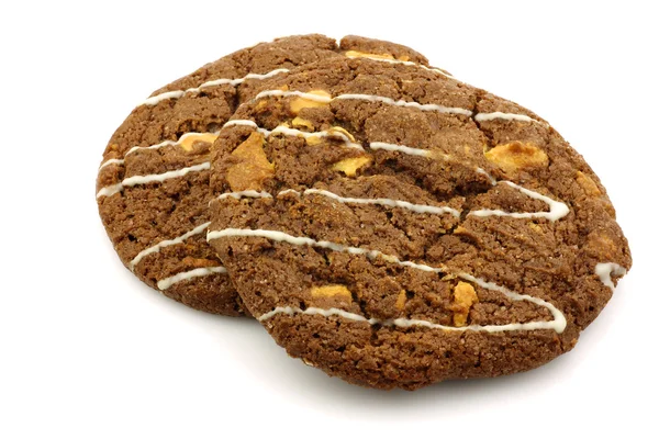 Dois biscoitos de chocolate crocantes com nozes decoradas com chocolate branco — Fotografia de Stock