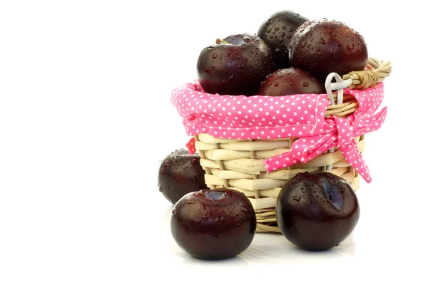 stock image Fresh plums in a wicker basket with pink dotted cloth