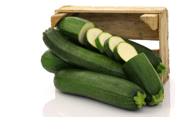 Fresh zucchini's and a cut one in a wooden box — Stock Photo, Image