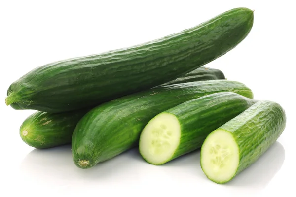 Three fresh cucumbers and a cut one — Stock Photo, Image