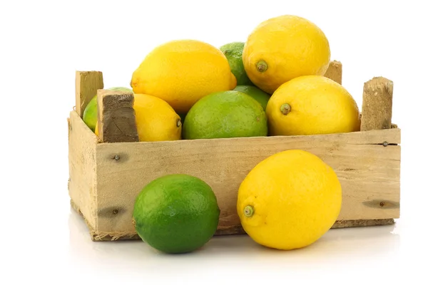 Fresh lemons and lime fruit in and around a wooden box — Stock Photo, Image