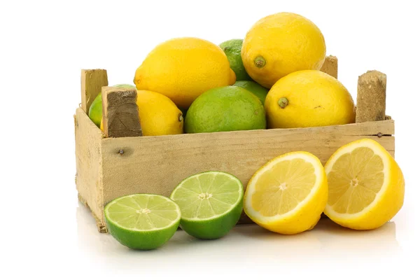 Färska citroner och lime frukter och några skär dem i och runt en trälåda — Stockfoto