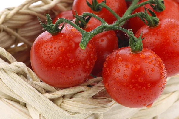Red cherry tomatoes in a woven basket — Stock Photo, Image