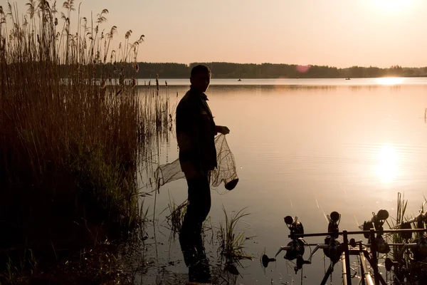 Рибалка рибалить на заході сонця — стокове фото