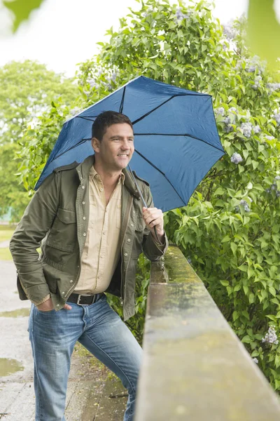 Man in park met blauw paraplu — Stockfoto