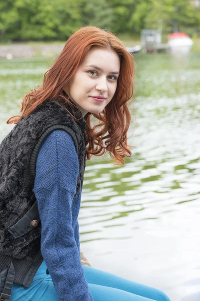 Junge Frau sitzt an einem See lizenzfreie Stockfotos