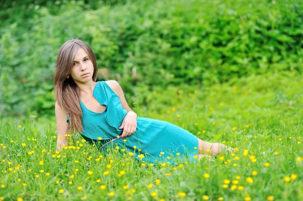 Junges süßes Mädchen liegt im Gras in der Nähe der offenen Fläche — Stockfoto