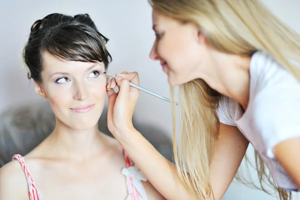 Jovem noiva bonita aplicando maquiagem de casamento por artista de maquiagem — Fotografia de Stock