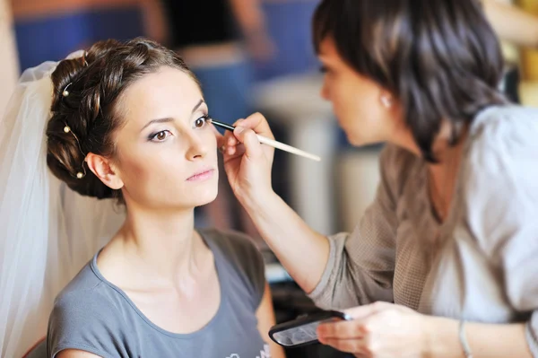 Unga vackra brud tillämpa bröllop make-up av make-up artist — Stockfoto