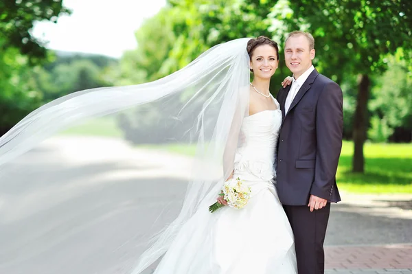 Happy bride and groom in a park — Stock Photo, Image