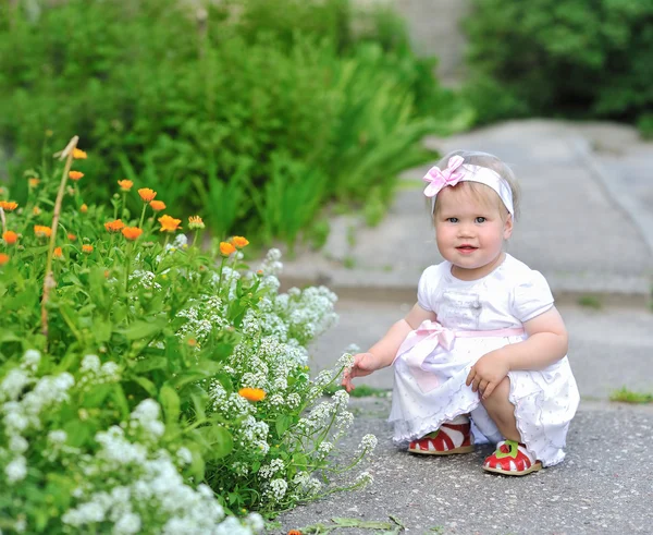 Schattig meisje spelen met bloemen buitenshuis — Stockfoto