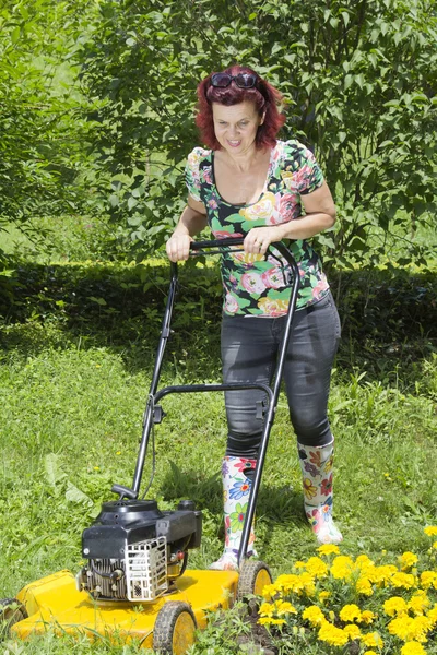 Улыбающаяся женщина стрижет траву — стоковое фото